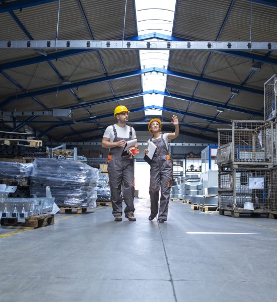 Factory workers walking through large production hall.